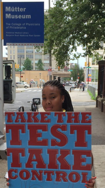 Person holding a poster promoting National Black HIV/AIDS Awareness Day. The Sign reads: "Take the Test. Take Control"