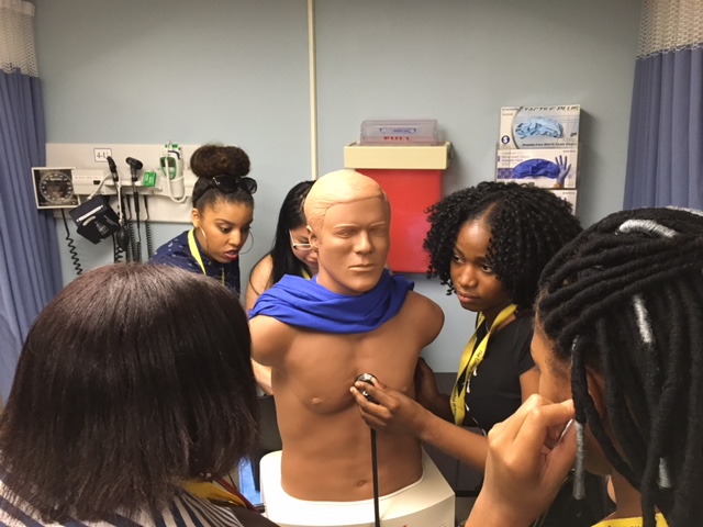Students in the Teva Pharmaceuticals Internship program practice taking vitals on a medical dummy at the Drexel University Physical Therapy Labs