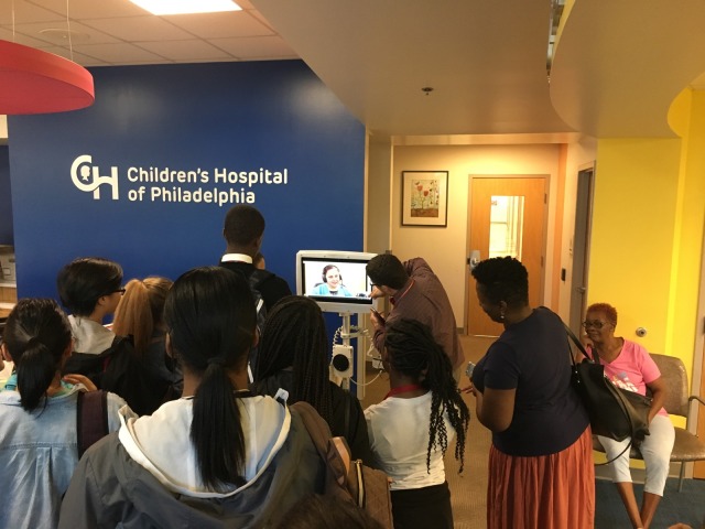 Students in the Karabots Junior Fellows Program interact with a medical interpreter on a scree at the CHOP Karabots Pediatric Care Center